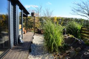 uma passagem de madeira ao lado de uma casa com plantas em Wellness Bed & Breakfast Pergamo em Voorhout