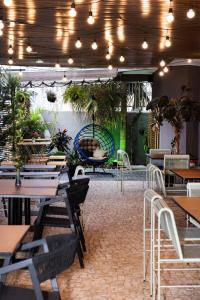 un restaurante con mesas, sillas y macetas en Hotel Parati Minas, en Uberlândia