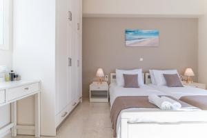 a white bedroom with two beds and two lamps at Helios Residence in Chania