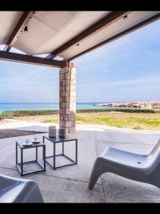 a patio with two tables and a chair and the ocean at Villa Aegina in Khlóï +5 photos