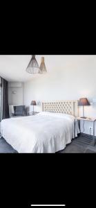 una camera con un grande letto bianco e due lampade di Villa Aegina a Khlóï