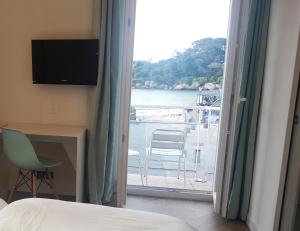 sypialnia z balkonem z widokiem na wodę w obiekcie Hotel De L'Europe w mieście Perros-Guirec
