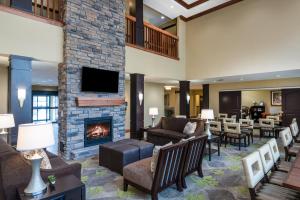 a hotel lobby with a fireplace and chairs and tables at Staybridge Suites Eau Claire - Altoona, an IHG Hotel in Altoona