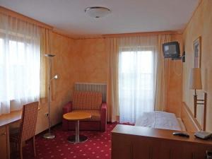 Cette chambre comprend un lit, une chaise et un bureau. dans l'établissement Ferienhotel Herzog, à Neumarkt am Wallersee