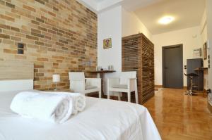 a bedroom with a white bed and a brick wall at A modern rustic cosy apartment at the foot of Mount Lycabettus in Athens