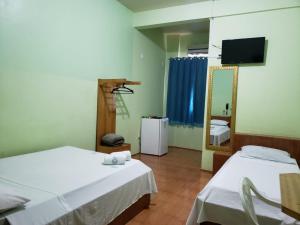 a room with two beds and a tv and a mirror at Hotel Chalé Ji-Parana in Ji-Paraná