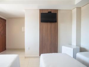 a bedroom with a bed and a tv on a wall at Hotel Barra Do Riacho, Aracruz in Barra do Riacho