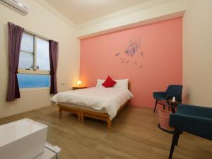 恆春的住宿－恆春奕棧民宿，一间卧室设有一张床和红色的墙壁