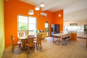 cocina con paredes de color naranja, mesa y sillas en 屏東的家, en Ho-p'ing-hsin-ts'un