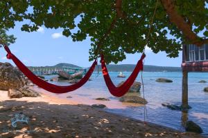 a couple of red hammocks hanging from a tree on a beach at Samloem Laguna Resort in Koh Rong Sanloem