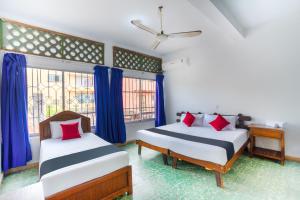 Dos camas en una habitación con cortinas azules. en Hotel Adelita, en Zihuatanejo