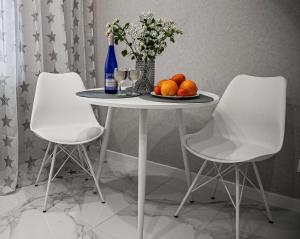 een tafel met twee witte stoelen en een fles en fruit bij Favorite Family Flat in Bila Tserkva