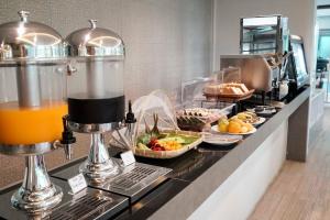 a buffet line with food and drinks on a counter at Nantra Chiangmai Riverfront Hotel in Chiang Mai