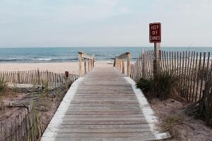 a wooden boardwalk leading to the beach with a for sale sign at Holiday Inn Express Stony Brook-Long Island by IHG in Centereach