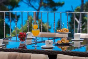 une table avec un verre de jus d'orange et une assiette de nourriture dans l'établissement Villa Mlini with private Pool and Sea view, à Mlini