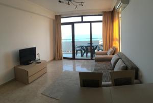 a living room with a couch and a television at Lazur 1-5 Apartments Complex in Sveti Vlas
