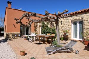Mas Uranie في Le Soler: فناء به طاولة وشجرة أمام المنزل