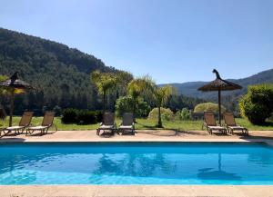 a group of chairs and umbrellas next to a swimming pool at Finca Hotel Son Pont in Puigpunyent