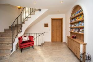 a staircase with a red chair and a book shelf at Chiemsee Hauszeit in Bernau am Chiemsee