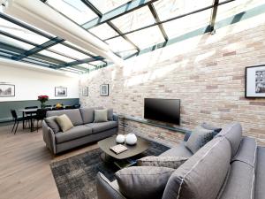un soggiorno con divani e un muro di mattoni di LivinParis - Luxury AC 3 Bedrooms Le Marais I a Parigi