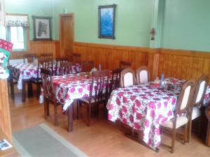 a dining room with tables and chairs with red and white table cloth at Hostal El Rincón in Puerto Natales