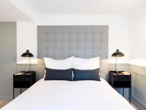ein Schlafzimmer mit einem großen weißen Bett mit zwei Lampen in der Unterkunft LivinParis - Luxury 4 Bedrooms Le Louvre I in Paris