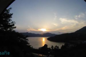 a sunset over a body of water with the sun setting at Chalet Itomic L in Hakone