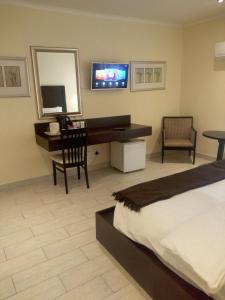 a bedroom with a bed and a desk and a television at Villa Via Hotel Midrand in Midrand
