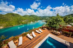a deck with chairs and a swimming pool next to a river at Villa On The Bay - Relaxed Elegance in Marigot Bay