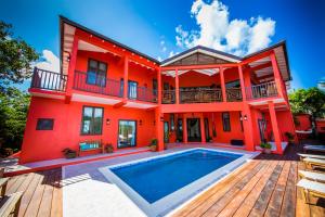 a red house with a swimming pool in front of it at Villa On The Bay - Relaxed Elegance in Marigot Bay