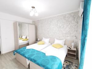 a white bedroom with two beds and a mirror at Otopeni Comfort Apartaments in Otopeni