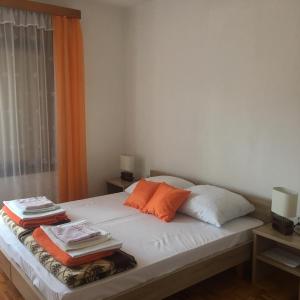 a bed with orange and white pillows and a window at Apartment Marija Selce in Selce