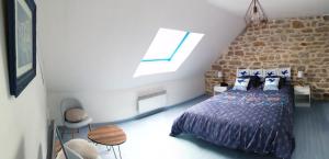 een slaapkamer met een bed en een stenen muur bij La Glycine in Fouesnant