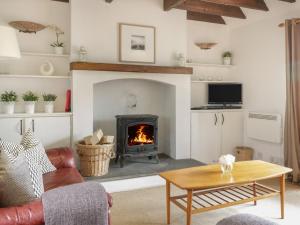 a living room with a fireplace and a table at Sweetpea Cottage in Wiston