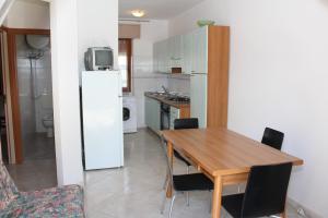 a kitchen with a wooden table and a refrigerator at Villa Debby appartamento 01 in Rosolina Mare