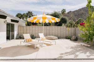 - une terrasse avec 2 chaises et un parasol dans l'établissement Villa Reel Paradise - Mid Century House, à Palm Springs
