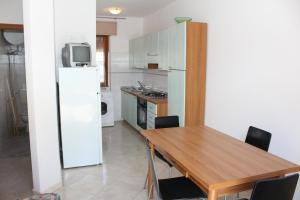 a kitchen with a wooden table and a white refrigerator at Villa Debby appartamento 01 in Rosolina Mare +13 photos
