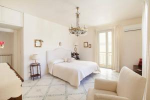ein weißes Schlafzimmer mit einem Bett und einem Kronleuchter in der Unterkunft Maison Du Tasso in Sorrent