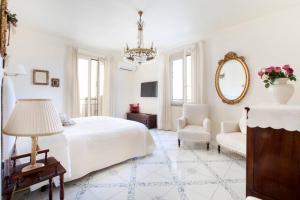 ein weißes Schlafzimmer mit einem Bett, einem Stuhl und einem Spiegel in der Unterkunft Maison Du Tasso in Sorrent
