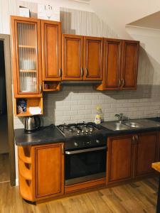 a kitchen with wooden cabinets and a black stove top oven at Hostel LaGoya z Restauracją in Nielisz
