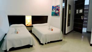 une chambre avec deux lits avec des draps blancs dans l'établissement Hotel Plaza Playa, à Playa del Carmen
