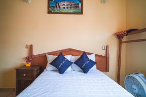 a bedroom with a bed with blue and white pillows at Capital O Hotel Aurora, Tuxtla Gutiérrez in Tuxtla Gutiérrez