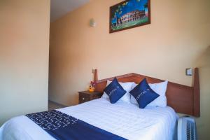 een slaapkamer met een bed met blauwe en witte kussens bij Capital O Hotel Aurora, Tuxtla Gutiérrez in Tuxtla Gutiérrez