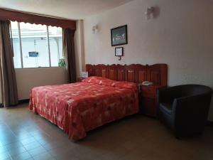 1 dormitorio con 1 cama roja y 1 silla en Hotel Cabildos en Tapachula
