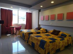 タパチュラにあるHotel Cabildosのベッド2台とテーブルが備わるホテルルームです。