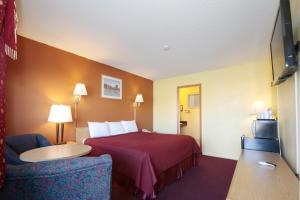 a hotel room with a bed and a chair at Regency Inn in Winnemucca