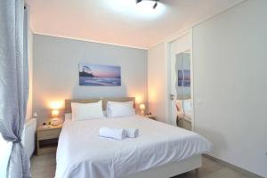 a bedroom with a white bed with two towels on it at Agia Paraskevi, a cozy and minimal retire in Athens