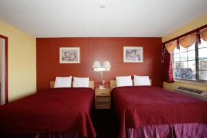 two beds in a hotel room with red walls at Regency Inn in Winnemucca