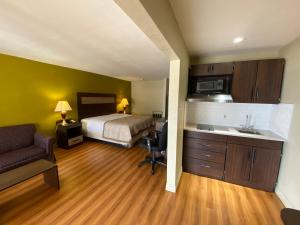 a hotel room with a bed and a kitchen with a sink at Stratford House Inn and Suites Temple in Temple