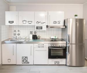 a kitchen with white cabinets and a stainless steel refrigerator at ARABEST Aparthotel & Boardinghouse in Munich